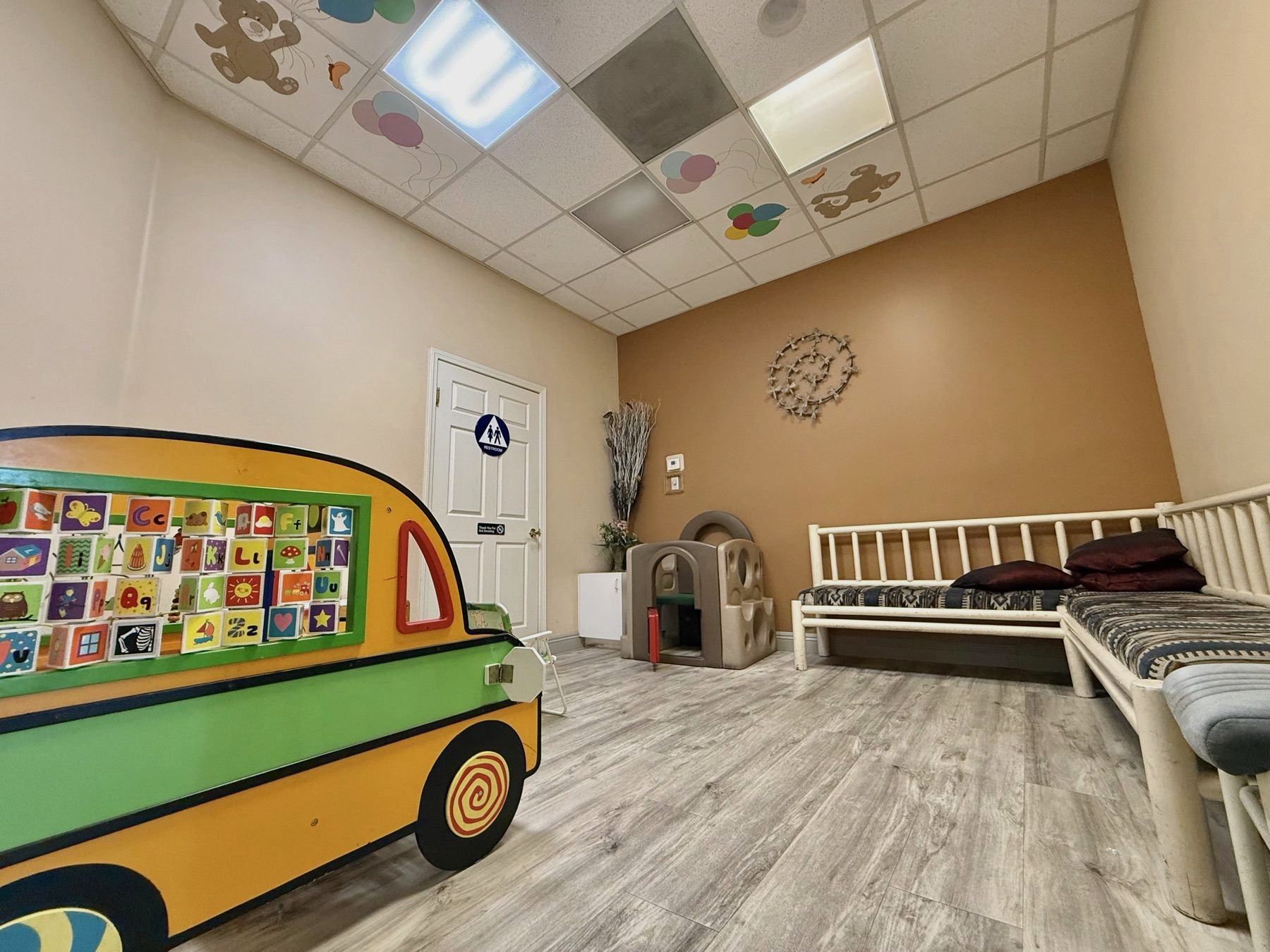 Colorful children's play area with a bus mural, alphabet blocks, and toys at Comfort Dental